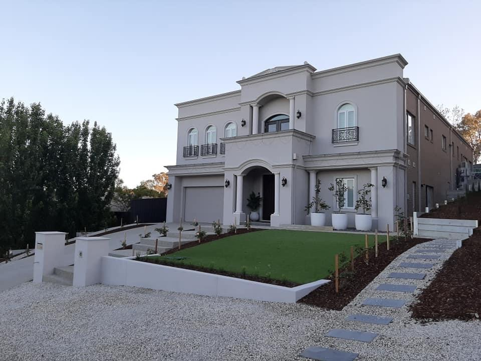 Two-storey rendered home with arched entryway and landscaped lawn